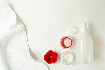 Spa and beauty.  A set of creams, a red flower and a white towel. Spa and cometology theme. Free space for text.