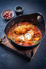 Modern style traditional slow cooked Italian veal roulades saltimbocca with vegetable and olives in spicy gravy sauce as close-up in a design pot 