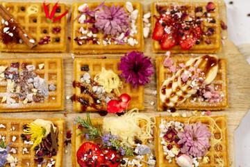 Waffles decorated on a wooden board with sweets blurred in background
