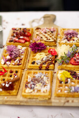 Waffles decorated on a wooden board with sweets blurred in background
