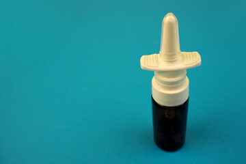 nose spray in a glass container and a white plastic cap side view on a blue background