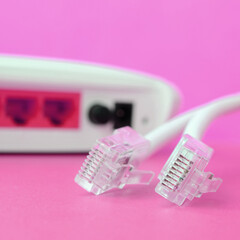 Internet router and Internet cable plugs lie on a bright pink background. Items required for...