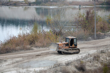 Quarry aggregate with heavy duty machinery. Caterpillar loader Excavator with backhoe driving to...