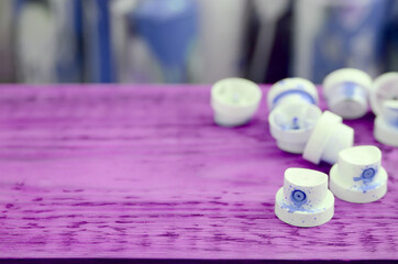 The soiled blue nozzles from the paint sprayer lies on a purple plank on a background of a many...
