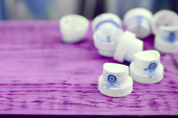 The soiled blue nozzles from the paint sprayer lies on a purple plank on a background of a many...