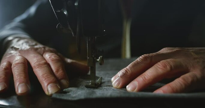 Cinematic macro shot of experienced tailor is sewing custom handmade high quality apparel in ancient luxury traditional tailoring atelier. Concept of industry, handmade, couturier and tradition.