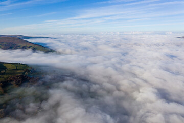Aerial view of mountains poking through a sea of fog and low cloud in a rural setting