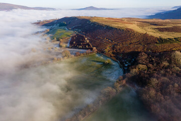 Aerial view looking down through fog on a frosty, frozen rural landscape (Wales)