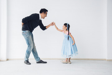 Father is teaching his little daughter to dance in the halls of the house. Happy holidays, family relationships.