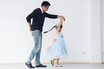 Father is teaching his little daughter to dance in the halls of the house. Happy holidays, family relationships.