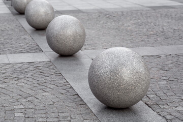 row of granite balls on the pedestrian sidewalk paved with stone tiles, cityscape urban street architecture, nobody.