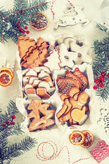 Top view of unpacked christmas present with sweets on a white textured surface framed by fir branches, close-up. Christmas celebration concept