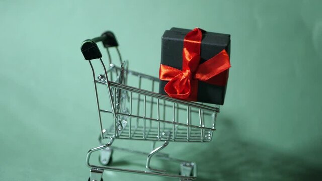 Levitate gift box with red ribbon bow. Shopping cart. Turquoise background. Holiday sale. Seasonal discount  