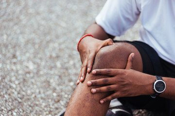 Close up Asian sport runner black man wear watch sitting he uses hands joint hold on his knee while running at the outdoor street health park, healthy exercise Injury from workout concept