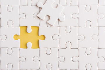 Fototapeta premium Top view flat lay of paper plain white jigsaw puzzle game texture incomplete or missing piece, studio shot on a yellow background, quiz calculation concept