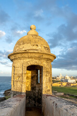 Turret at Castillo San Cristobal Fort with city in background at sunset in San Juan, Puerto Rico. It was built by Spain in 1783 to protect against land based attacks on the city of San Juan 