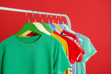 Obraz premium Rack with stylish children clothes on red background, closeup