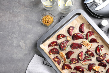 Baking tray with roasted beetroot slices on grey table, flat lay