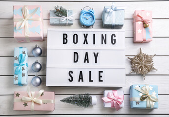 Flat lay composition with Boxing Day Sale sign and Christmas gifts on white wooden table
