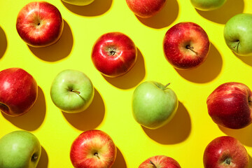 Many different ripe apples on yellow background