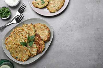 Delicious zucchini fritters served on grey table, flat lay. Space for text