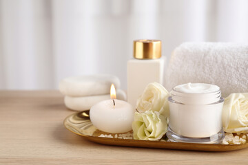 Fototapeta na wymiar Spa composition with skin care products, flowers and candle on wooden table. Space for text