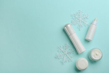 Flat lay composition with different cosmetic products on turquoise background, space for text. Winter care