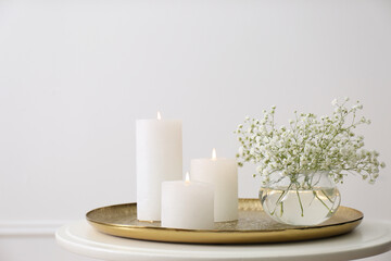 Vase with beautiful flowers and burning candles on table indoors. Interior elements
