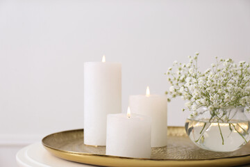 Fototapeta na wymiar Vase with beautiful flowers and burning candles on table indoors, closeup. Interior elements