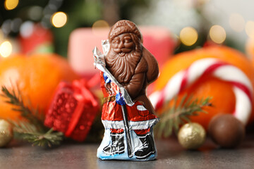 Chocolate Santa Claus candy against Christmas decorations, sweets and tangerine fruits