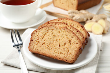 Slices of delicious gingerbread cake served with tea on white wooden table