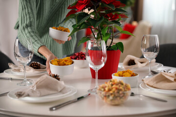 Woman setting table for Christmas dinner at home, closeup