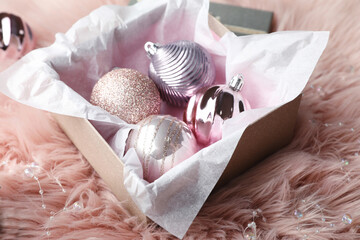 Beautiful Christmas baubles in box on pink faux fur