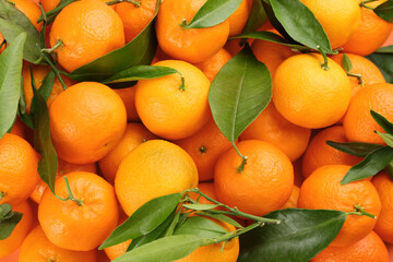 Fresh tangerines with green leaves as background, top view