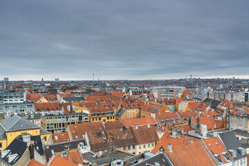 Fototapeta na wymiar Aerial view of old downtown of Copenhagen City from the The Round Tower (Rundetaarn) in rainy misty day with cloudy sky with red house roofs and churches