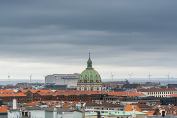 Fototapeta na wymiar Aerial view of Copenhagen City from the The Round Tower (Rundetaarn) in rainy misty day with cloudy sky and building of red roofs and Frederik's Church (Frederiks Kirke) and factories
