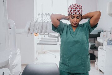 Young blond Caucasian female opening her mouth while African-American ethnic dentist in white latex...