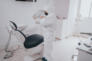 Young blond Caucasian female opening her mouth while African-American ethnic dentist in white latex gloves check condition of her teeth (focus on dentist)