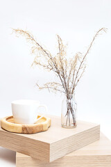 Pampas grass in glass vase on wooden table near white wall