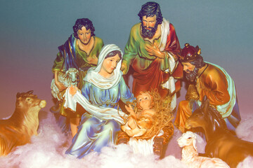 Fototapeta premium The traditional Nativity of Jesus represented with resin figures ideal for Advent and Christmas celebration depicting the holy family, a shepherd, a king and animals against gray background