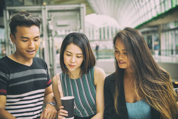Three asian friends in a mall shopping center drinking coffee and talking
