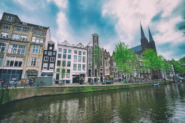 Obraz premium AMSTERDAM, THE NETHERLANDS - APRIL 25, 2015: Traditional houses and buildings on the canal
