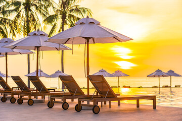 Umbrella and deck chair around outdoor swimming pool in hotel resort