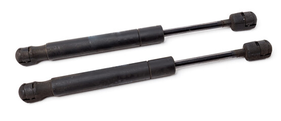 Fototapeta premium A pair of black metal hood shock absorbers with chrome elements - detail of a car mechanism on a white isolated background. Spare parts for body repair.