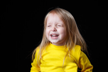 Portrait of an emotional beautiful little girl. Isolated on a dark background.