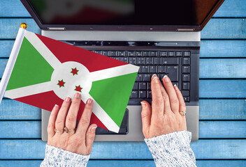 woman hands and flag of Burundi on computer, laptop keyboard 