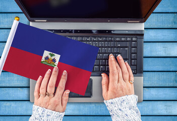 woman hands and flag of Haiti on computer, laptop keyboard 