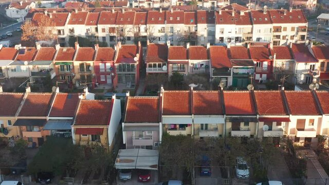 Rows of terrace houses in a mill town. Townhouses with red roofs in a company village or monotown in Europe. Housing project in suburban neighborhood. Aerial drone view.