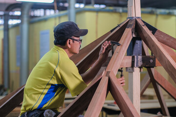 Carpenter using bolt and nut in installation of roof rafters on a new gazebo construction project .