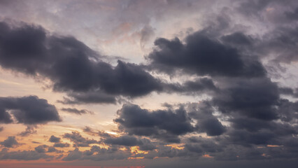 Disturbing sunset sky. Dusk. Dark clouds float, through which orange sunlight breaks through.